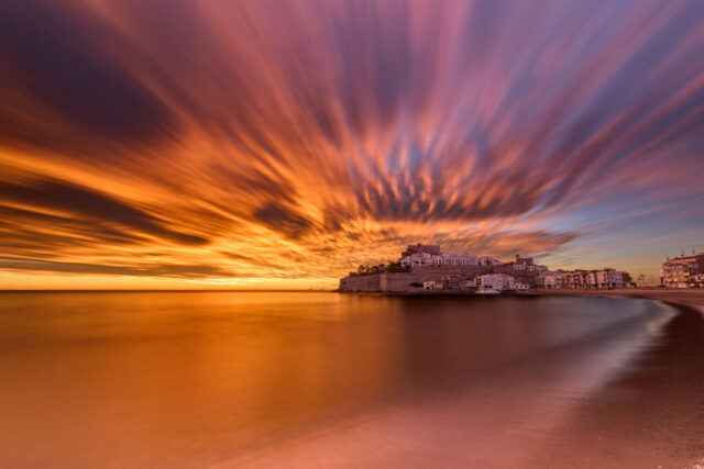 High contrast long exposure photograph of sunrise over Peñíscola beach with Peñíscola Castle in the background, Spain
