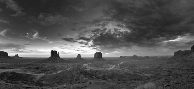 Black and white panoramic photograph of Monument Valley at sunset from a viewpoint