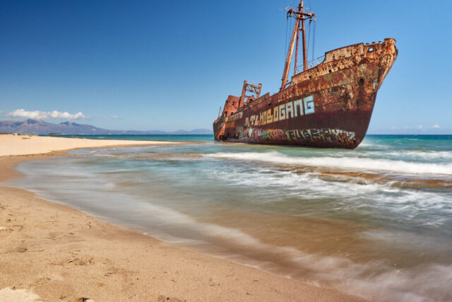 HDR long exposure landscape photograph of a shipwreck on the beach in Gytheio, Greece with soft water motion and coastal light