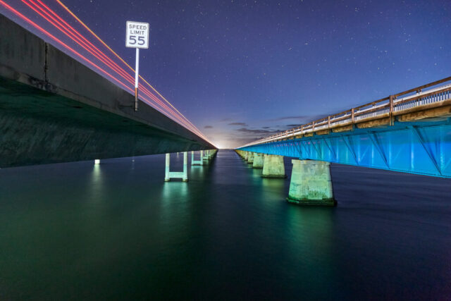 Long exposure image of the Seven Mile Bridge in Florida at night with light trails and water reflections